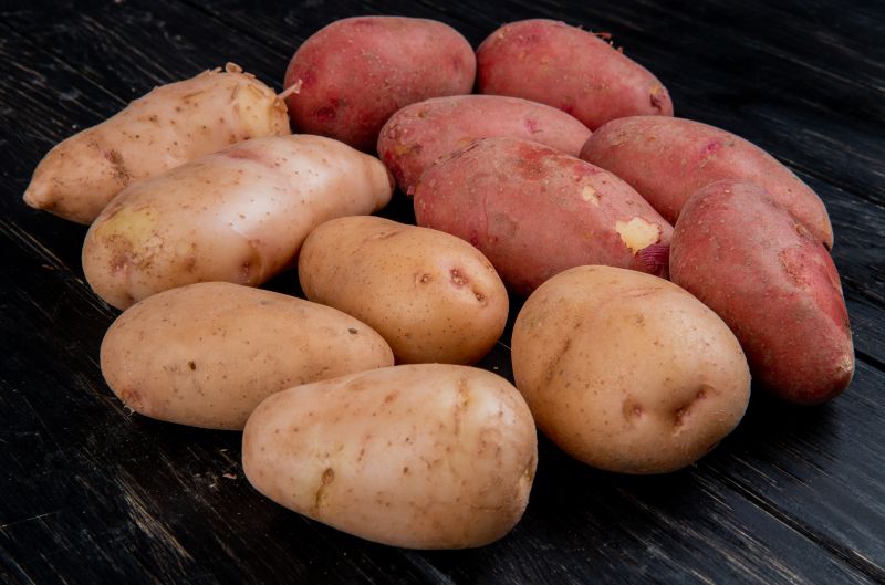 side view of white and red potatoes on wooden background